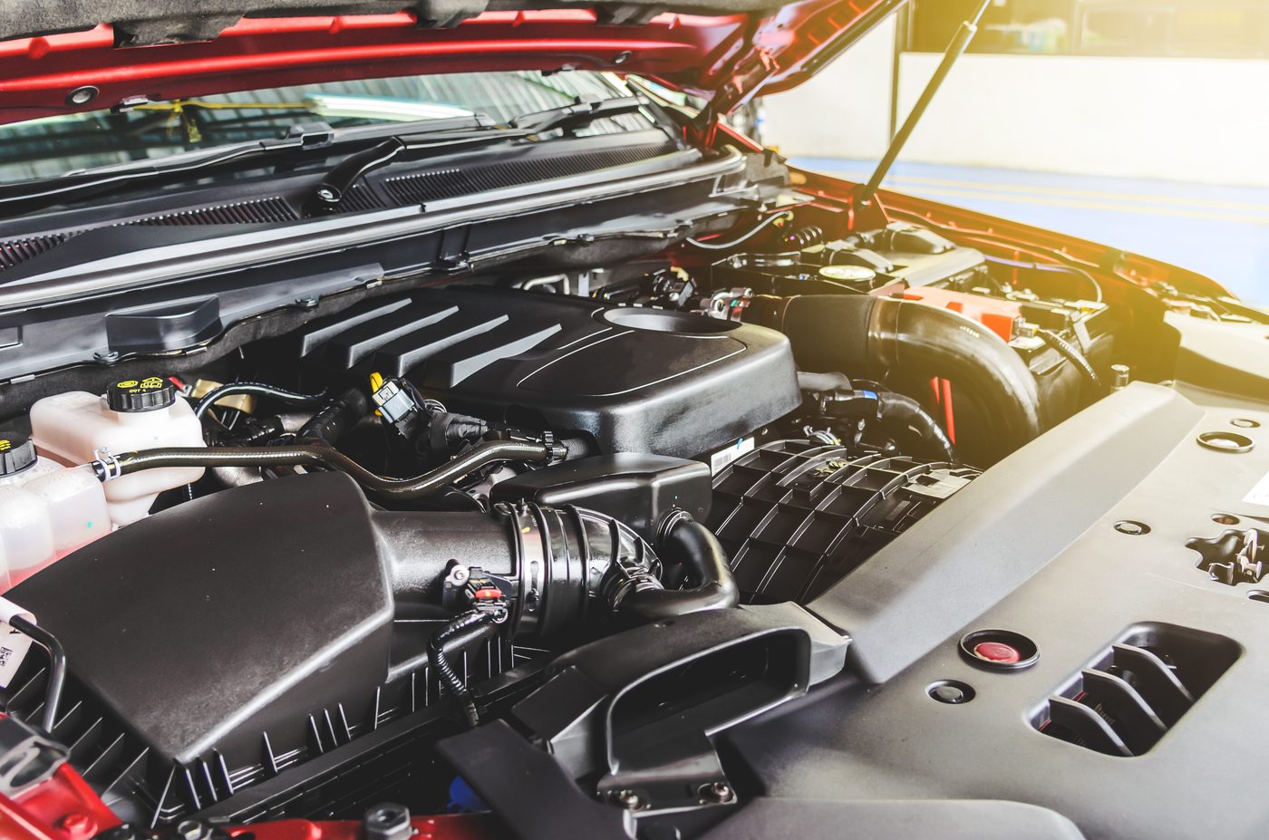 Car engine compartment inspected by technician